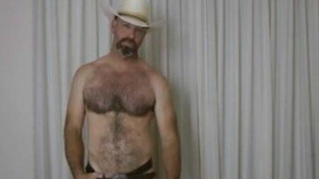 Cowboy polishes his belt buckle and squirts